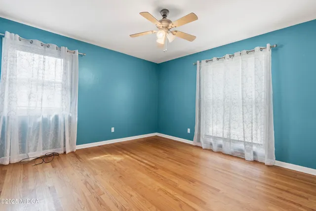 an empty room with wooden floor and windows