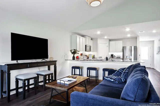 a living room with stainless steel appliances kitchen island granite countertop furniture and a wooden floor