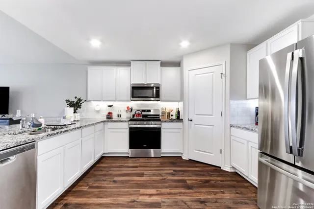 a kitchen with kitchen island granite countertop a refrigerator stove top oven and sink