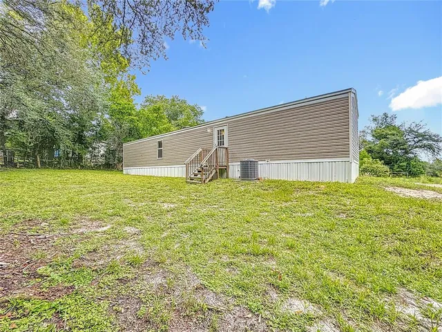 a backyard of a house with large trees and plants