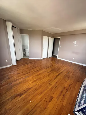 a view of an empty room with wooden floor and windows