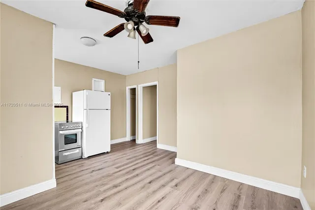 a view of a kitchen with a refrigerator a ceiling fan and wooden floor