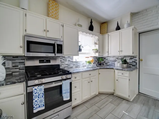a kitchen with granite countertop white cabinets stainless steel appliances and sink