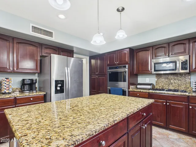 a large kitchen with wooden floors stainless steel appliances a window and a center island