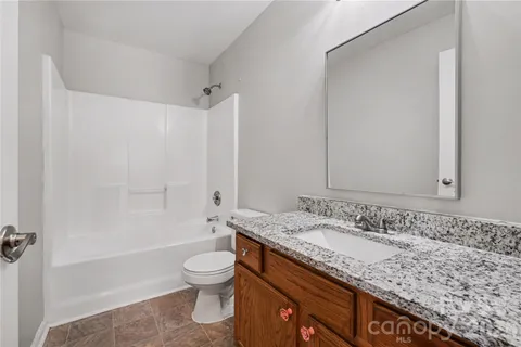 a bathroom with a granite countertop sink a toilet and shower
