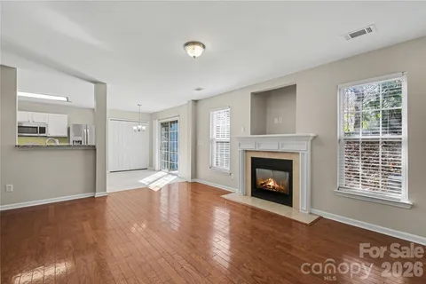 a view of an empty room with wooden floor fireplace and a window