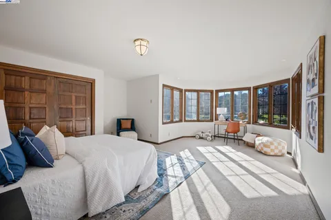 a spacious bedroom with a bed and wooden floor