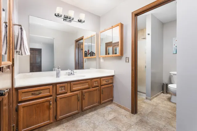 a view of a hallway with wooden floor and a bathroom