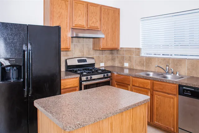 a kitchen with granite countertop a refrigerator stove and sink