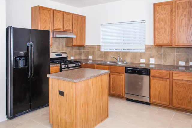 a kitchen with stainless steel appliances granite countertop a refrigerator a sink a stove and white cabinets