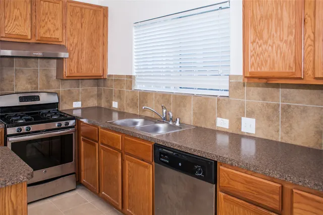 a kitchen with stainless steel appliances granite countertop a sink stove and cabinets