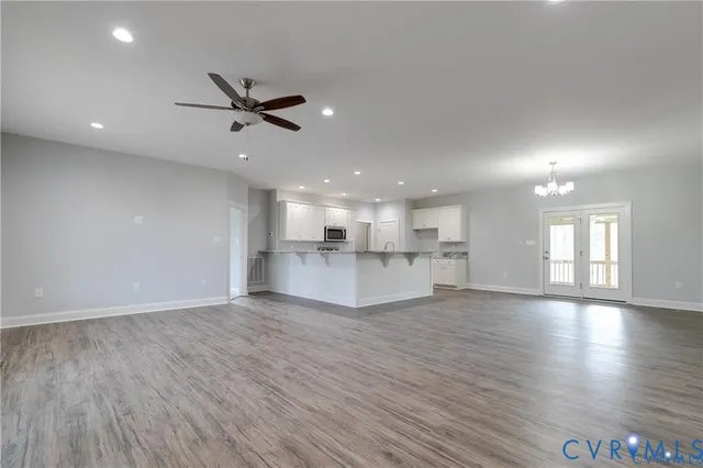 a view of an empty room with window wooden floor and a kitchen