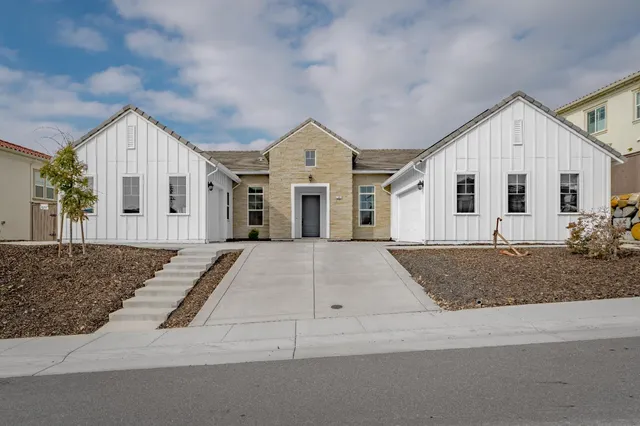 a view of a white house next to a yard