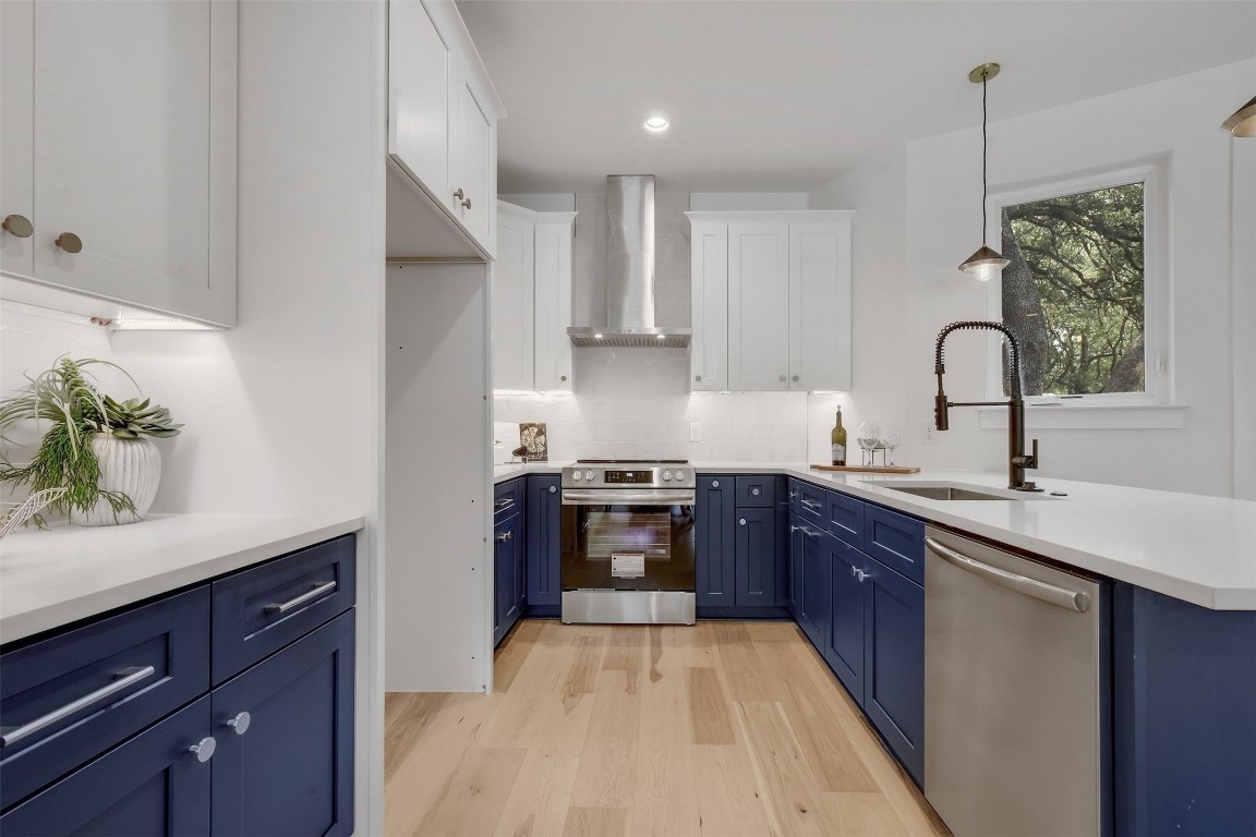 a kitchen with stainless steel appliances granite countertop a stove a sink dishwasher and a refrigerator with wooden floor