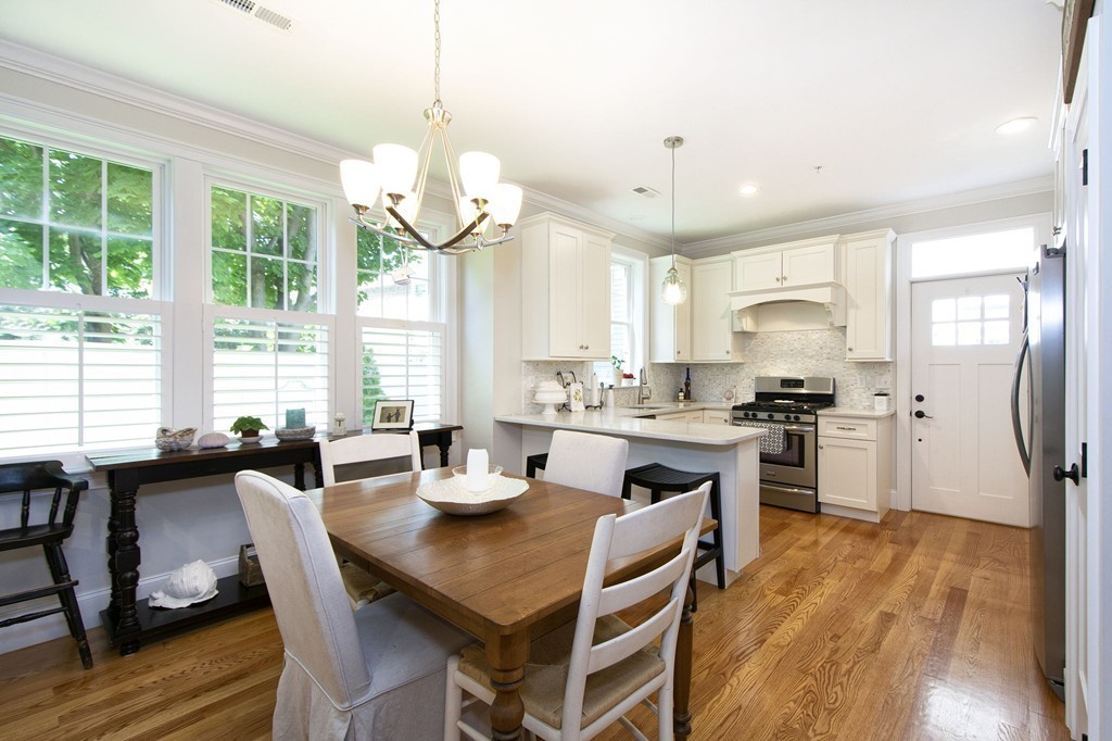 95 First Parish Road, Unit 2 Scituate, MA 02066 - Photo 2 of 19 a kitchen with stainless steel appliances granite countertop a stove a refrigerator a kitchen island a sink dishwasher a dining table and chairs with wooden floor