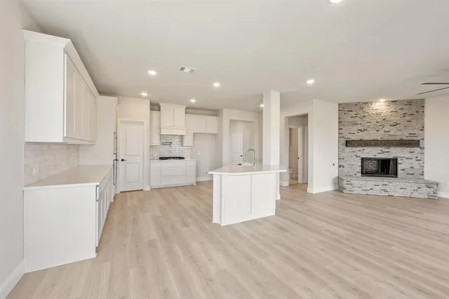 a view of a kitchen with kitchen island wooden floor center island stainless steel appliances and cabinets
