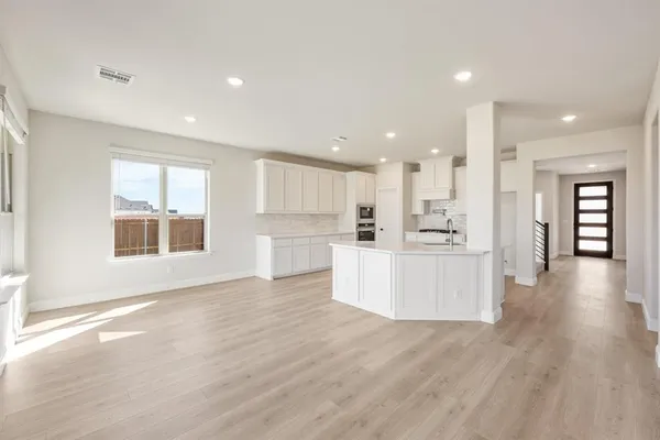 a view of a kitchen with kitchen island wooden floors appliances and a window