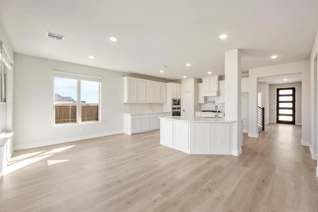 a view of a kitchen with kitchen island wooden floors appliances and a window