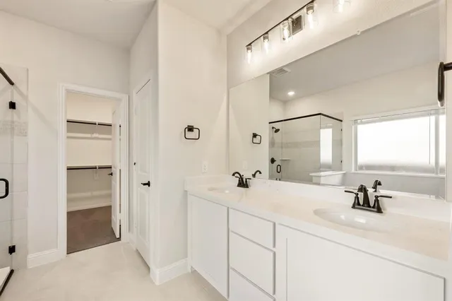 a bathroom with a double vanity sink mirror and shower