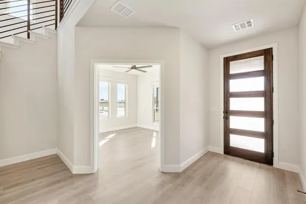 an empty room with wooden floor closet and windows