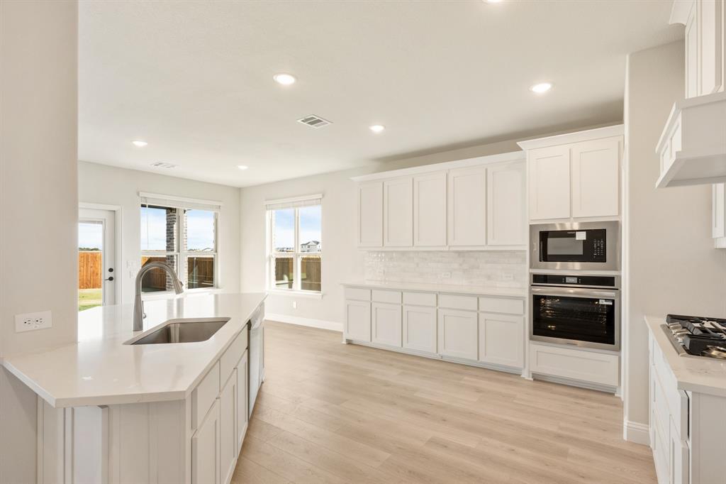 2000 Hickory Chase Lane Anna, TX 75409 - Photo 7 of 40 a kitchen with granite countertop a refrigerator oven a sink dishwasher and white cabinets with wooden floor