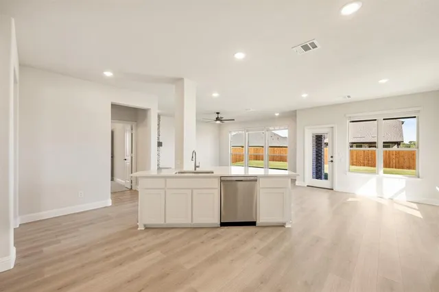 a large white kitchen with a sink and dishwasher a refrigerator with wooden floor