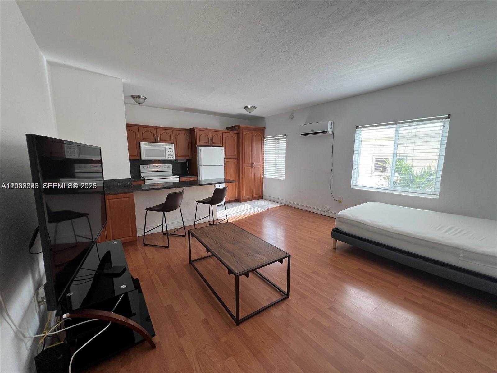 7920 Harding Avenue, Unit 9 Miami Beach, FL 33141 - Photo 3 of 13 a living room with furniture a flat screen tv and a wooden floor