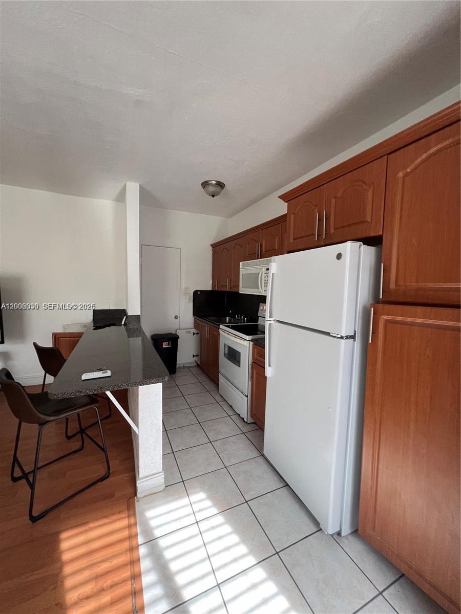 7920 Harding Avenue, Unit 9 Miami Beach, FL 33141 - Photo 7 of 13 a kitchen with stainless steel appliances a refrigerator sink and cabinets