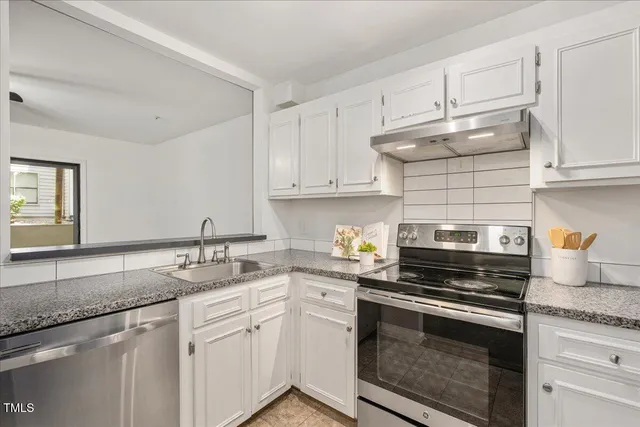 a kitchen with granite countertop a sink stainless steel appliances and cabinets