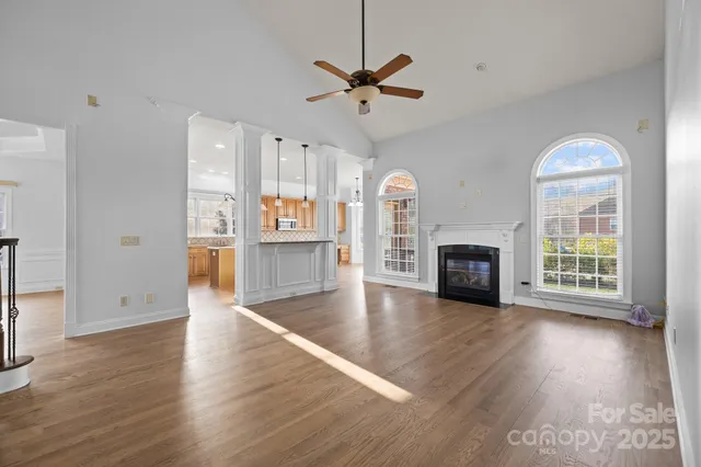wooden floor in an empty room with a fireplace and a window