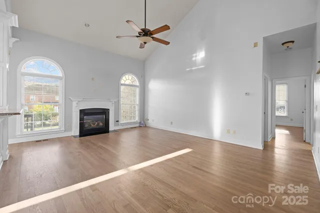 a view of a livingroom with wooden floor a ceiling fan and windows