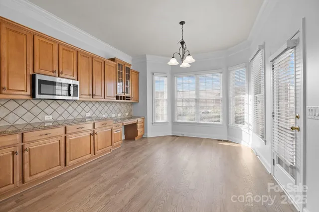 a large kitchen with stainless steel appliances granite countertop a stove a sink dishwasher a microwave oven with cabinets and wooden floor