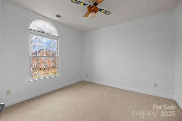 an empty room with a window and a ceiling fan