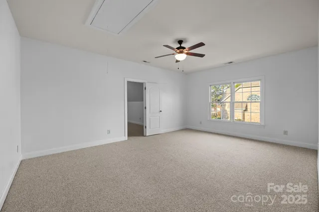 an empty room with windows and ceiling fan