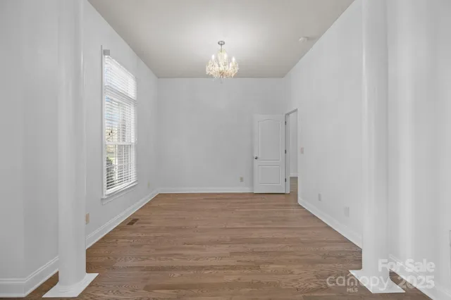 a view of an empty room with window and chandelier fan