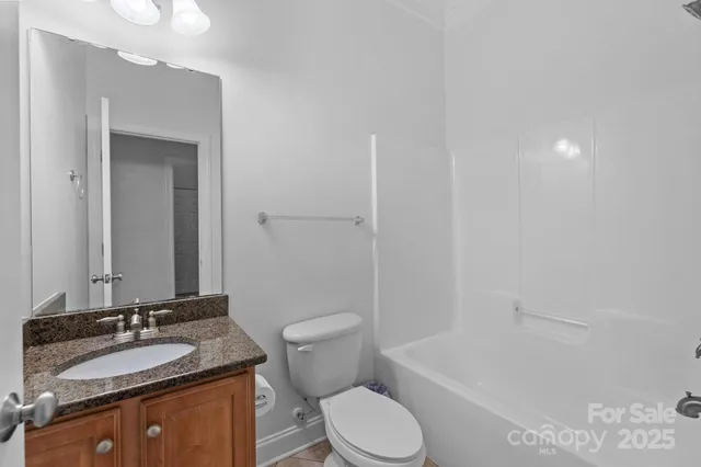 a bathroom with a granite countertop sink toilet a mirror and shower