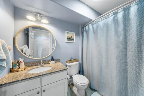 a bathroom with a granite countertop sink toilet and a mirror