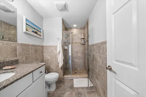 a bathroom with a granite countertop toilet a sink and shower