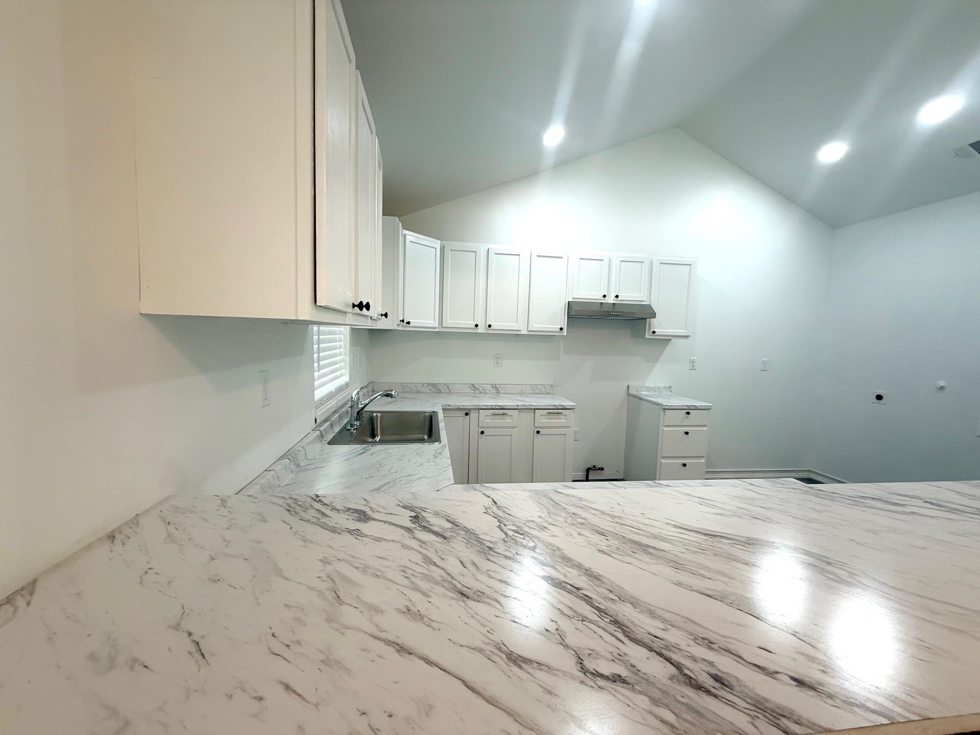 3054 Lotus Road Memphis, TN 38109 - Photo 12 of 29 Kitchen featuring extensive white cabinetry, large undermount stainless steel sink, patterned countertops, and recessed lighting