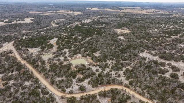 an aerial view of residential houses with outdoor space and trees
