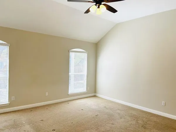 an empty room with a ceiling fan and carpet