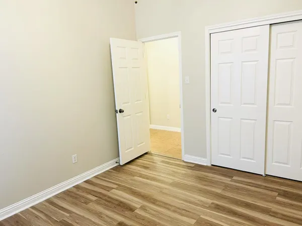 an empty room with wooden floor and closet area