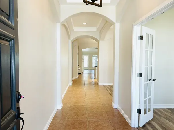a view of a hallway with wooden floor and a bathroom