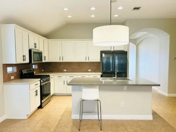 a kitchen with stainless steel appliances granite countertop a stove a sink and a microwave