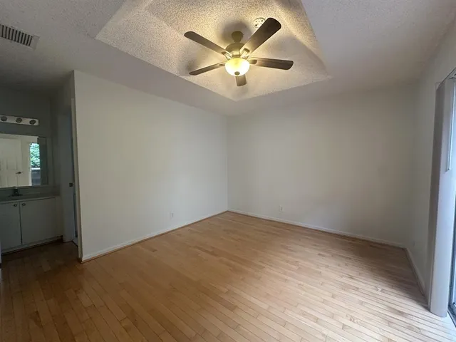 an empty room with wooden floor and ceiling fan