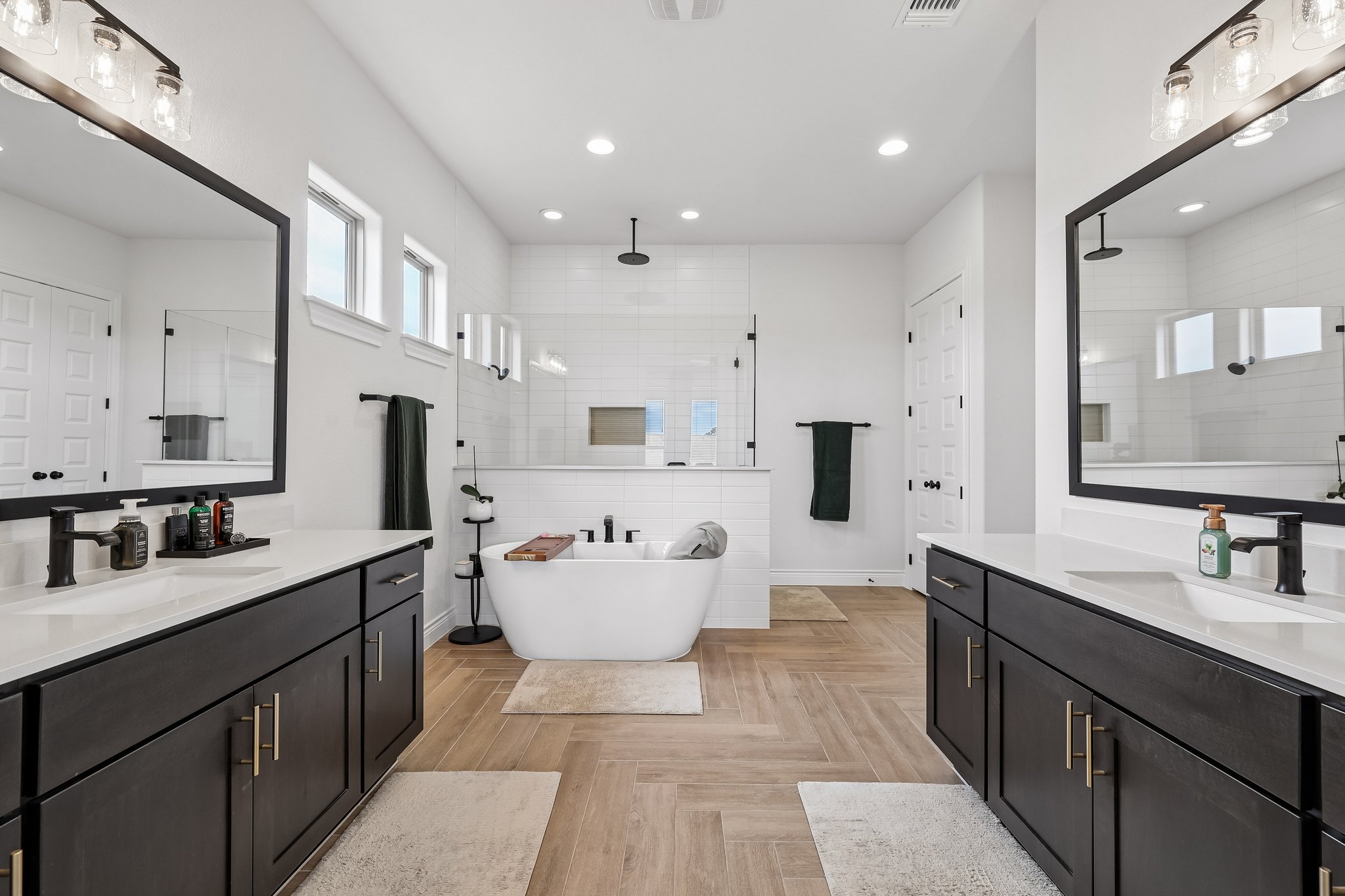 130 Firethorn Loop Bastrop, TX 78602 - Photo 21 of 38 Spacious bathroom featuring dual vanities with dark cabinetry and white countertops, a freestanding soaking tub, and a separate glass-enclosed shower with white subway tile