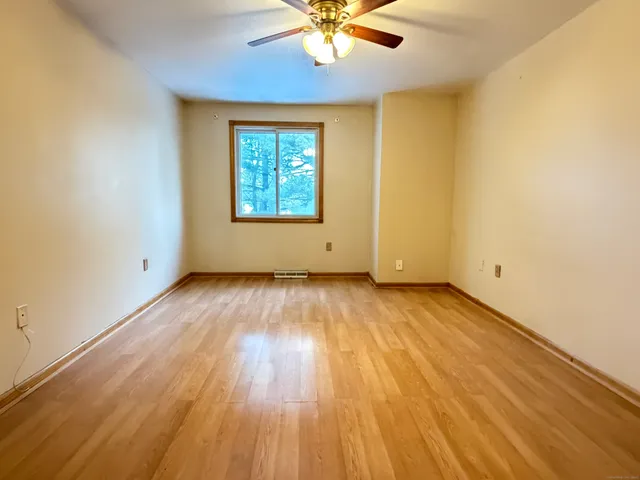 an empty room with wooden floor chandelier fan and windows