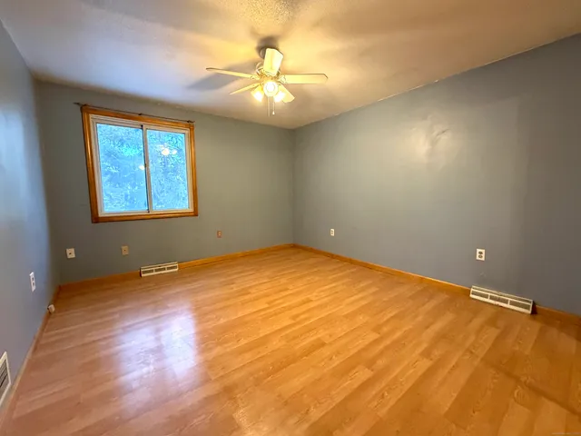 an empty room with a chandelier fan and windows