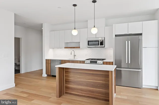 a kitchen with a refrigerator a sink and wooden floor