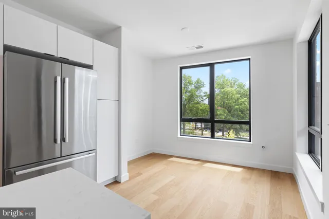 a view of an empty room with a window and wooden floor